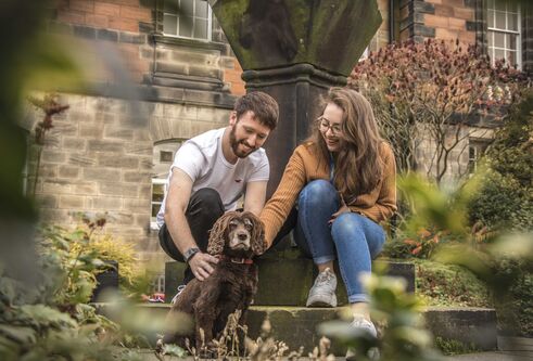Young man and woman with brown fluffy dog in the Geddes Quadrangle