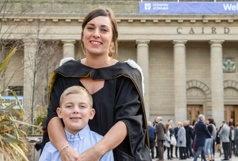 Charlotte in a graduation gown with her son in front of Caird Hall