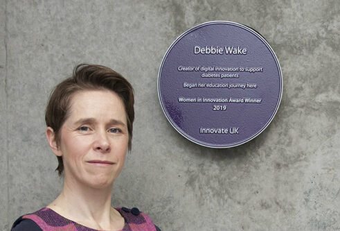 Debbie Wake standing next to her plaque