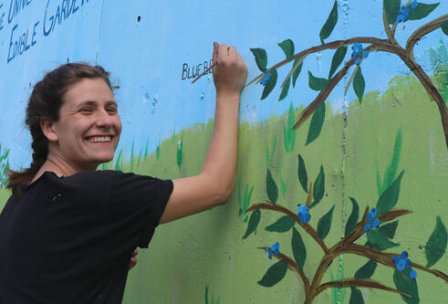 Alexis Bernstein painting a garden mural