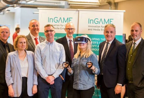 A group of people, one of whom is wearing a VR headset