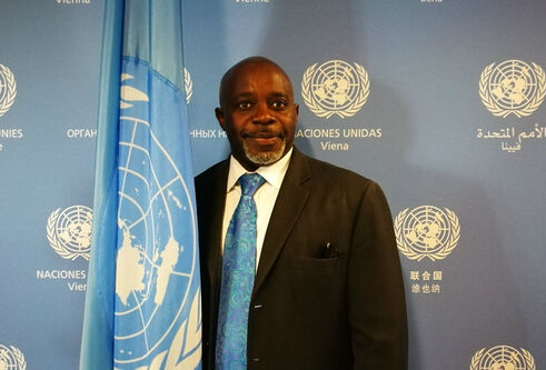 Justice Tettey stands beside a UN flag