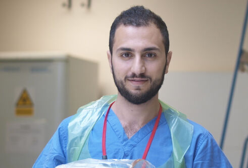 Rawad Qaq in scrubs with an apron on
