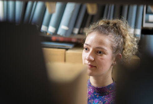 Girl looking at old books in an archive