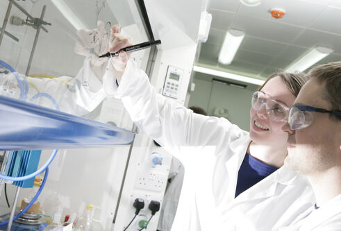 people in PPE writing on a transparent surface with permanent marker