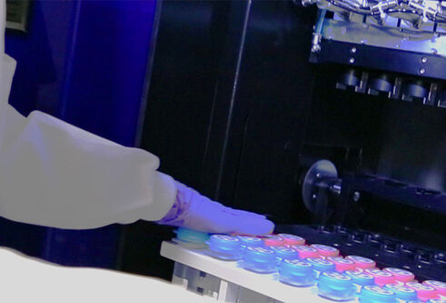 A person in PPE moving samples into or out of a fridge