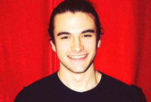 a headshot with a red background behind him