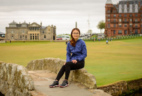 Yan Jiang sitting on the Swilken Bridge in St Andrews, on the Old Course
