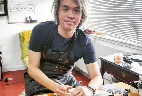 an image of Frank sitting at a desk drawing