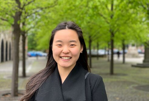 Wan Nee standing in front of green trees