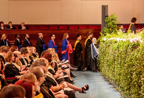 a queue of graduands at the side of the caird hall as they prepare to cross the stage