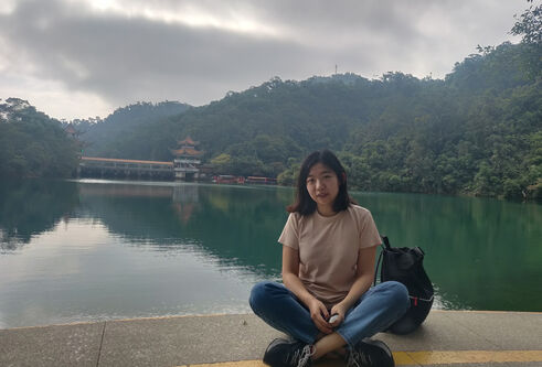 Ding Wang sitting in front of a lake