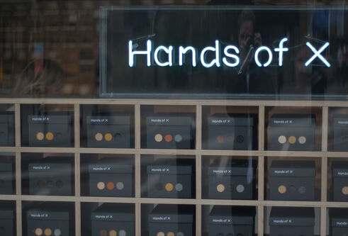 a rack of pigeonholes containing boxes with coloured dots on them, and the title 'hands of x' above