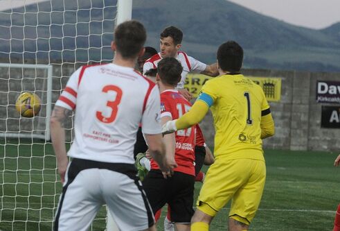 4 men playing football and goalposts in the background