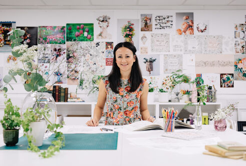 Hohanna with a wall behind her covered in drawings of flowers