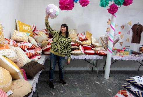 Nikki in a room with brightly coloured flowers and lots of cushions behind her