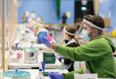A man sitting in a Covid testing centre holding a syringe