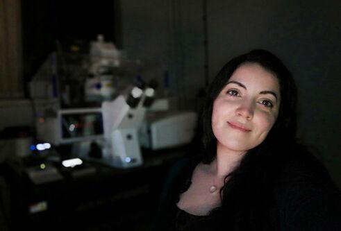woman standing next to microscope in dark room