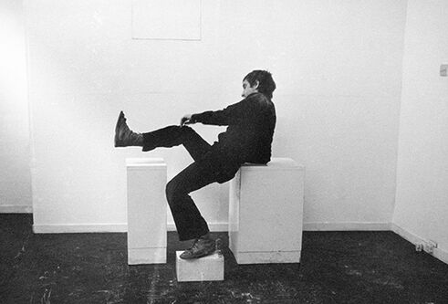 Man sat on white boxes, raising one leg