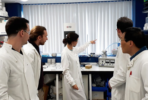 people in lab coats standing in a group in a lab