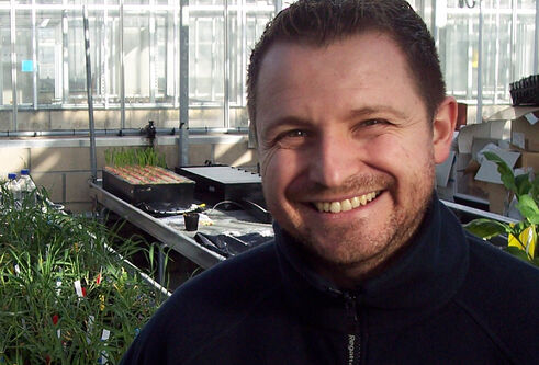 man standing in front of trays of plants