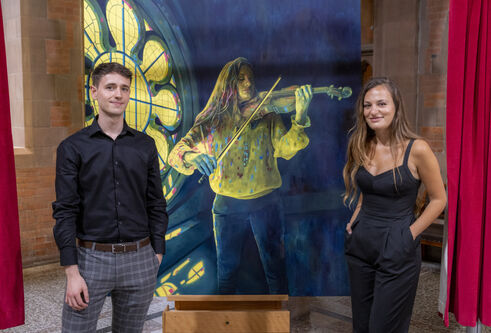 Artist Calum Stevenson stands beside musician Nicola Benedetti and a portrait of her that he painted