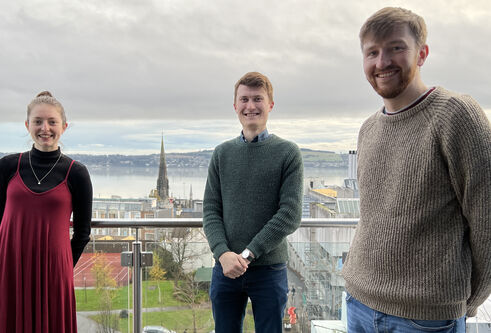 three students standing together outside overlooking Dundee