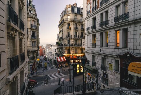 A series of stairs descent between streets of Montmartre in Paris, there are many restaurant and cafe signs in French on the buildings around