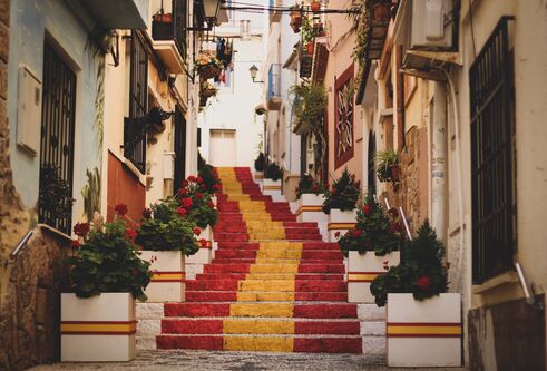 A set of steps painted in the red and yellow colours of the Spanish flag rise through an old town centre.