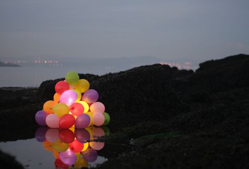 Colourful balloons in the foreground and dark landscape behind