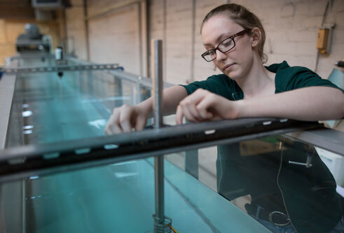 Girl working with water tank equipment in fluid mechanics lab.