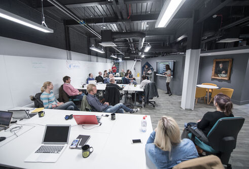 Students listen to a presentation in a room with coworking desks