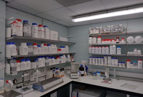 bottles of solutions on shelving in lab