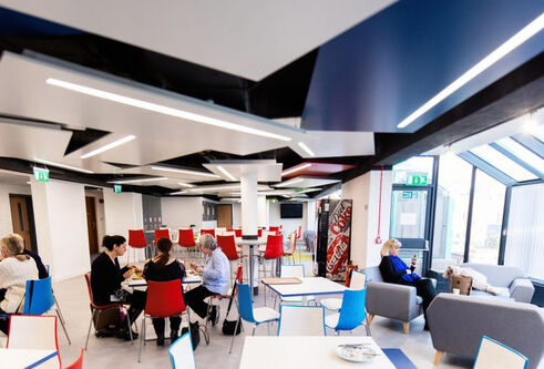 students in large airy cafe style space with large glass windows
