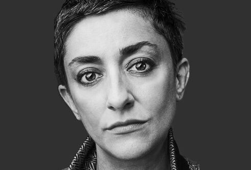Maria Fusco black and white portrait against a dark grey background.