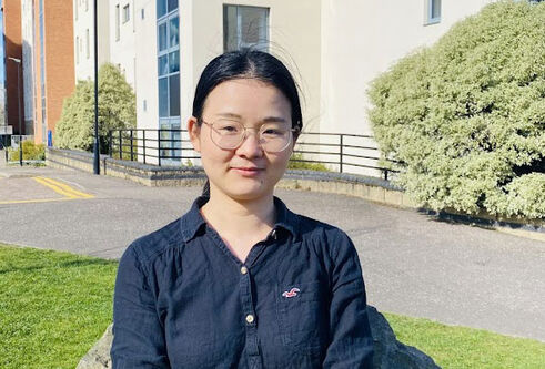 Xingui sits outside some buildings on the university campus.