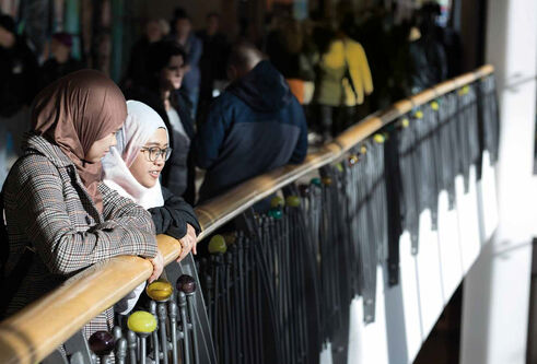 Two girls standing looking out over a balcony