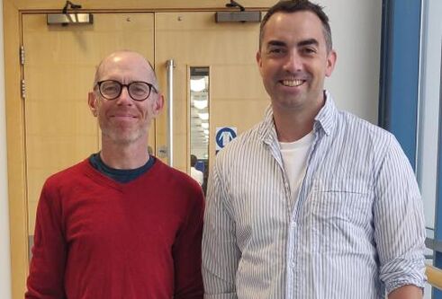 Dr Stephen Mathes and Dr David Millrine standing in front of an office door