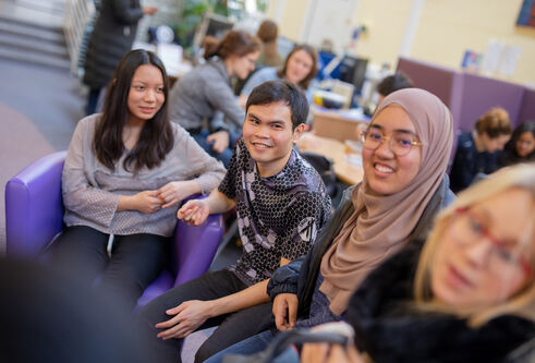 Candid photo of four seated students smiling