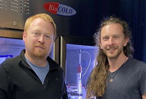Dr David Murray and Dr Hannes Maib standing in front of a lab refrigerator