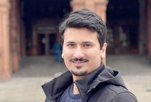 Romail Mukhtar standing outside a red brick building