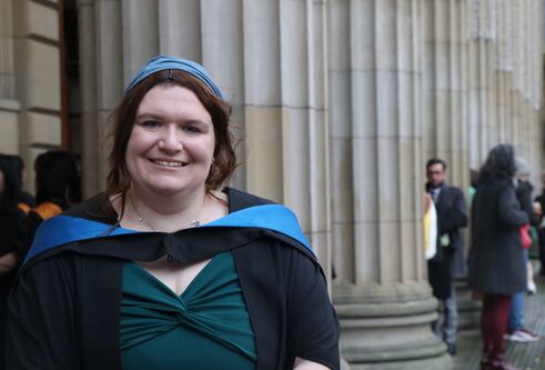 Sophie, dressed in her graduation robes, standing outside the Caird Hall