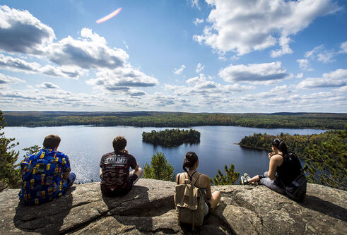 Students sitting on cliff overlooking lake