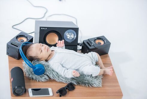 Baby lying back listening to music on headphones