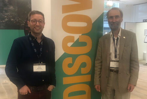 Dr Sean Whittaker and Prof Colin Reid standing in a lobby next to a column with the word Discovery