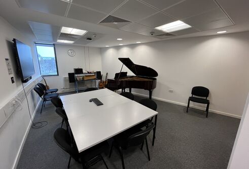 Dalhousie 1S11 - music room with a piano and tables set in a square with chairs