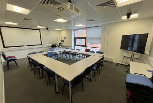Dalhousie 2S02 - tables and chairs with a mobile tv screen and white screen at far wall