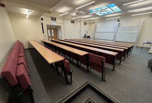 Fulton room J20 with cushioned seats attached to rows and two large white boards at the front of the room