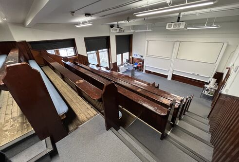 Old Medical School room 2.03 with old wooden benches and two large white screens