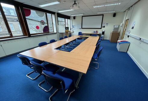 Tower T8 has a table set up in a boardroom style with a white screen at the front